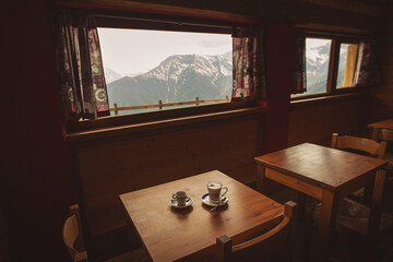 cups of espresso and cappucino against the mountains. hot coffee on wood table in wooden lodge at...