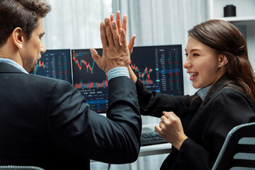 Successful in two business traders making hands high five with fist up to earn highest profit stock...