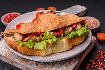 Delicious fresh crispy croissant with chicken or beef meat, lettuce, tomatoes, spices and sauce