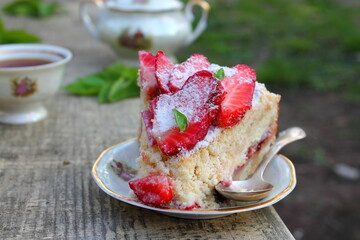 Piece of Strawberry pie on a plate served on a wooden table with green grass background. Summer homemade cakes with fresh berries. Family breakfast. Slow living concept