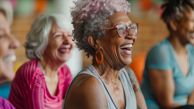 Elderly women laughing and sitting together in yoga studio.