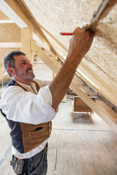 Construction woodworker measuring on site of attic conversion