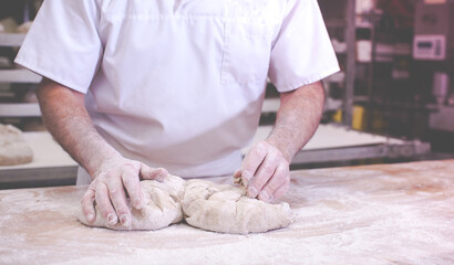 close-up on hands of baker in bakery kneading dough to bake fresh bread in the morning - 760059751