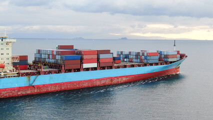 Aerial view of a large, loaded container cargo ship traveling over open ocea
