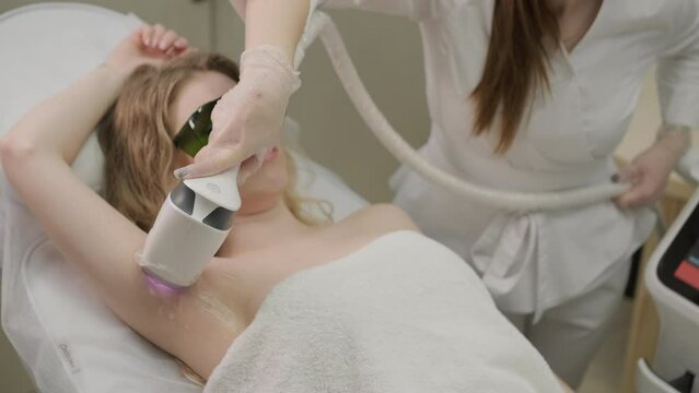 Woman armpit area during procedure of laser hair removal in modern cosmetology clinic. Concept of women beauty, cosmetology, epilation