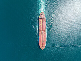 Aerial top view of cargo maritime ship with contrail in the ocean ship carrying container and running for export concept technology freight shipping by ship forwarder mast