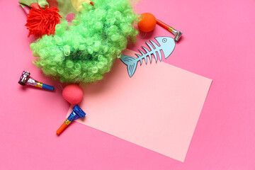 Blank card with paper fish, clown wig and party whistles on pink background. April Fools Day...