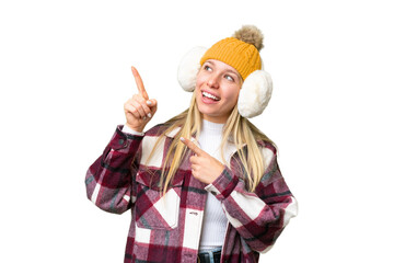Young pretty blonde woman wearing winter muffs over isolated chroma key background pointing with...