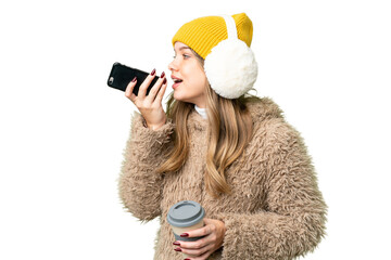 Young girl wearing winter muffs over isolated chroma key background holding coffee to take away and...