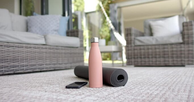 A yoga mat and water bottle rest on a patio