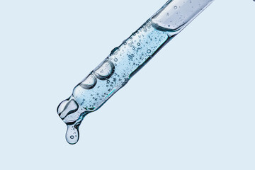 Cosmetic dropper pipette with drop transparent texture  on blue background