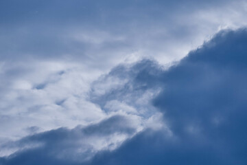 Niebo lekko zachmurzone, częściowo pokryte białymi chmurami, zza których widać błękit nieboskłonu. - obrazy, fototapety, plakaty