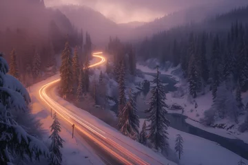  Road in winter forest in the mountains illuminated by passing cars with headlights on, view from above © Alina Zavhorodnii