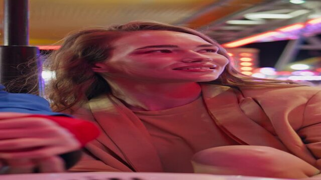 Girls rest amusement park in carousel vertical closeup. Two smiling friends