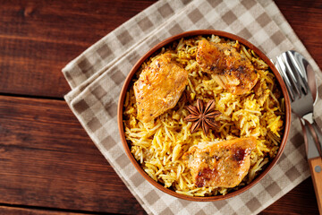 Chicken Biryani with Fried Chicken and Star Anise on Wooden Table Served with Linen Napkin and Cutlery, Copy Space, Top View