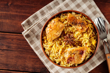 Chicken Biryani with Fried Chicken and Star Anise on Wooden Table Served with Linen Napkin and...
