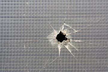 Loch in einem zerstörten Fenster aus Sicherheitsglas - obrazy, fototapety, plakaty