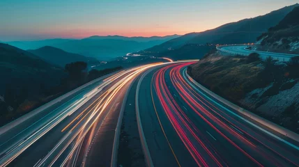 Wandcirkels plexiglas Motion blur from cars driving on a winding scenic road at twilight © Georgina Burrows