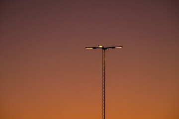 Flood lights on a tall mast in the evening.