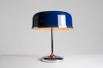 The lamp's lampshade is colored in cobalt, casting a calming glow against the retro table lamp, isolated on white.