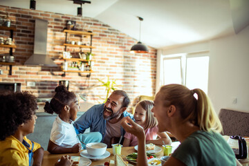 Young mixed family eating together at home