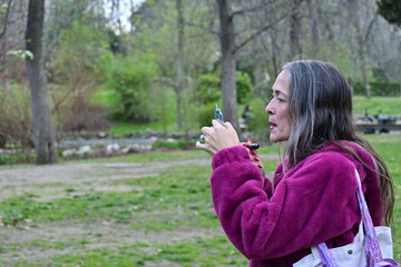 Woman applying her make-up while walking in a park