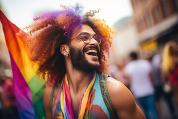 A young handsome man with curly hair and a rainbow flag at a pride parade