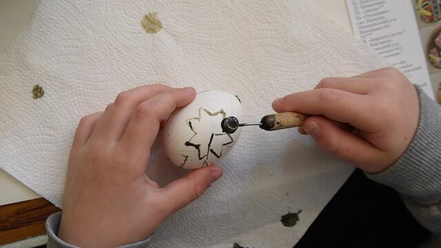 A child dying Easter egg with with Wax and Dye method