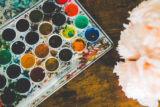 Messy Watercolors with Flowers: Used Watercolor Paints on Brown Table with Peach Peonies in Corner, Artist Behind the Scenes with Watercolors