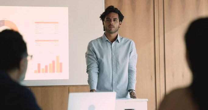 In modern office young Mexican businessman lead corporate conference on finances. Analyzing data and sharing expertise, interacts, engages audience, exchanging opinions and ideas for business progress