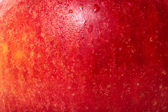 The texture of an apple is red with yellow. Apple skin with water drops.
