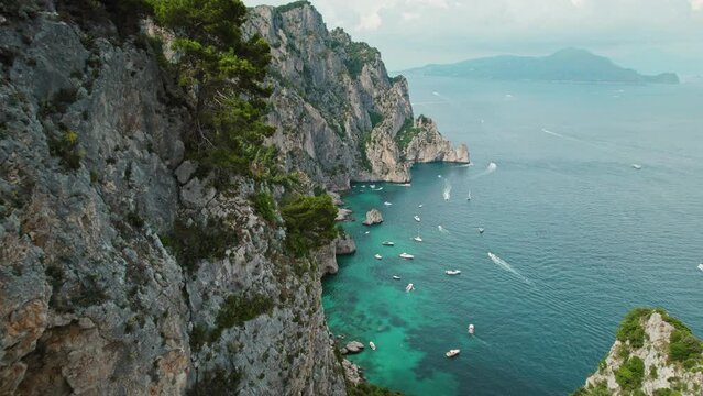 Green cliffs of Capri overlook the serene sea, inviting relaxation on a sunny Italian summer day.