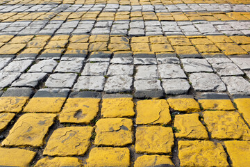 Cobblestone pavement painted with white and yellow stripes, pedestrian crossing, brick road - background is blurred, bokeh, selective focuse