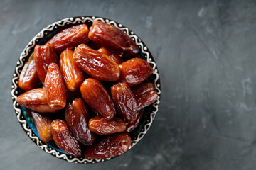 Dried Dates in Bowl on Concrete Surface, Top View, Copy Space