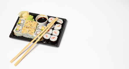Sushi to go in a black takeaway box with wooden chopsticks on white background