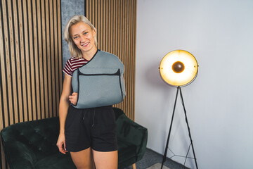 Young woman with a broken arm wearing an arm splint at home, home rehabilitation. High quality photo