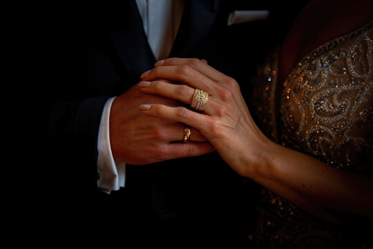 Elegant couple holding hands showcasing wedding rings. Generative AI image