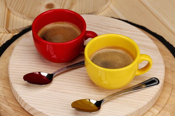 Tazzina rossa e gialla di caffè espresso all'italiana su sfondo di legno 