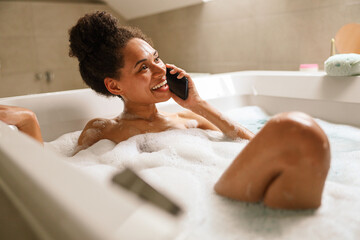 a woman is taking a bath and talking on a cell phone