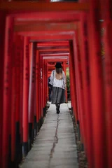 Fotobehang Woman walking through Torii gates © Paulo