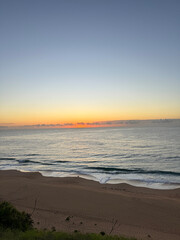 Fototapeta na wymiar Sunrise at a beach in Summer in Australia overlooking the horizon and ocean