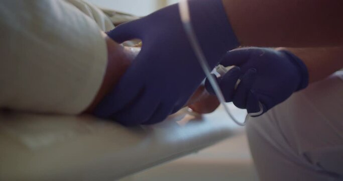Experienced and skilled male doctor giving IV drip or vitamin infusion to young patient.
