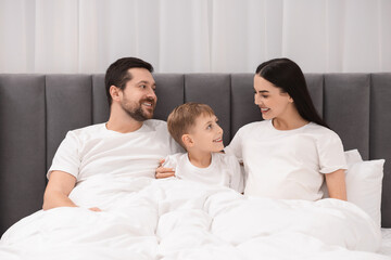 Obraz premium Happy pregnant woman with her son and husband in bed at home