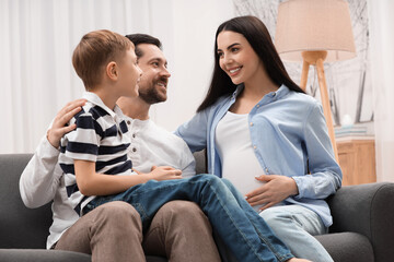Happy pregnant woman spending time with her son and husband at home