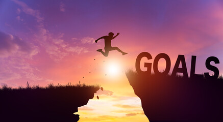 Silhouette man jumping form cliff to another mountain with Goals. Possible of Goals in business Concept. Copy space.