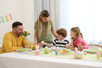 Obraz na płótnie Canvas Happy family celebrating Easter at served table in room