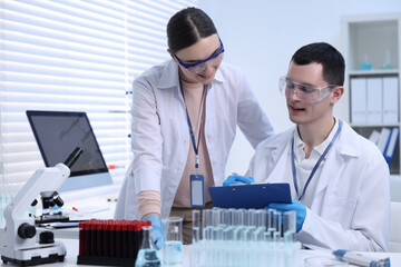 Scientists working with laboratory test form at table indoors