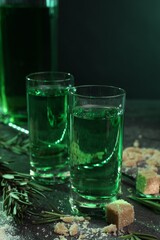 Absinthe in shot glasses, rosemary and brown sugar on table, closeup. Alcoholic drink