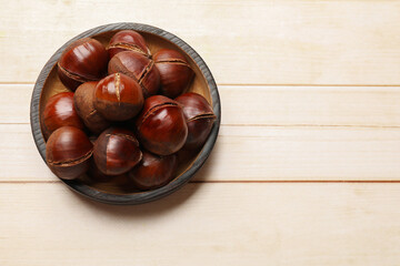 Roasted edible sweet chestnuts on wooden table, top view. Space for text