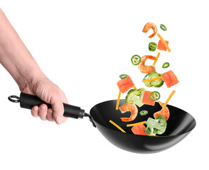 Man tossing ingredients in wok on white background, closeup